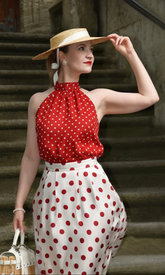 a lady in a red top and a white skirt with polka dots